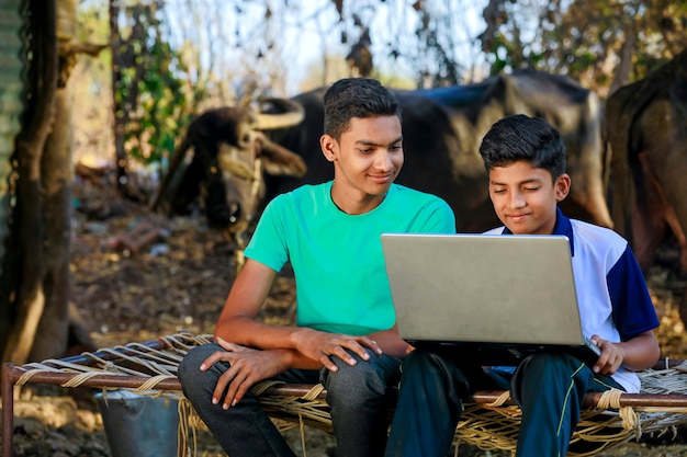 Piccolo ragazzo indiano / asiatico sveglio che studia o che gioca con il computer portatile