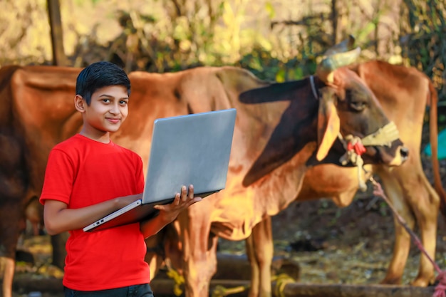 Piccolo ragazzo indiano / asiatico sveglio che studia o che gioca con il computer portatile