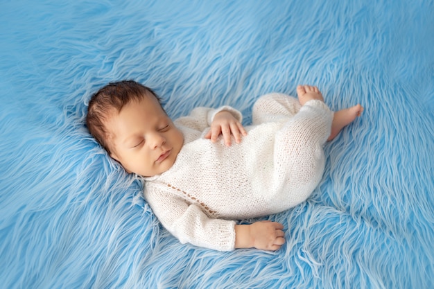 Piccolo ragazzo neonato che dorme sulla pelliccia blu