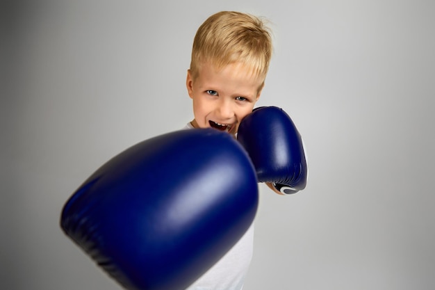 Piccolo ragazzo pugile con i guanti blu che combatte