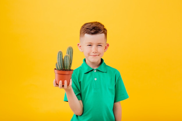 Piccolo ragazzo sveglio con un cactus in una pentola