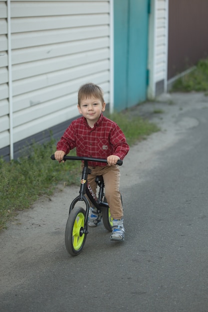 Piccolo ragazzo sveglio del bambino sulla bicicletta il giorno del autmn o di estate. Bambino felice in buona salute divertendosi con il ciclismo sulla bici.