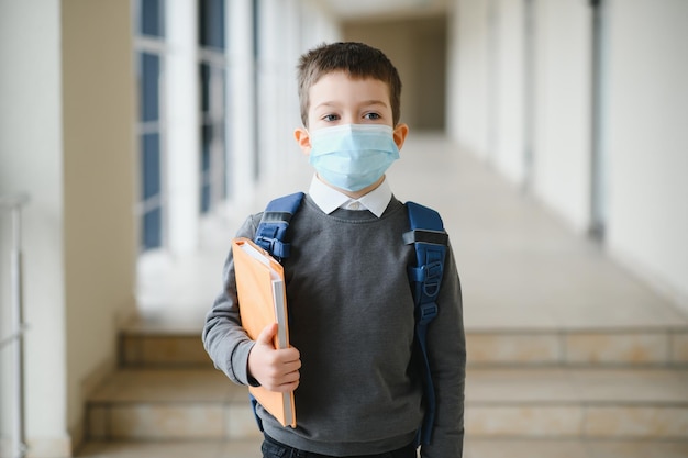 Piccolo scolaro che indossa una maschera durante un focolaio di protezione dal virus corona e influenzale contro le malattie dei bambini Maschera per la prevenzione del coronavirus