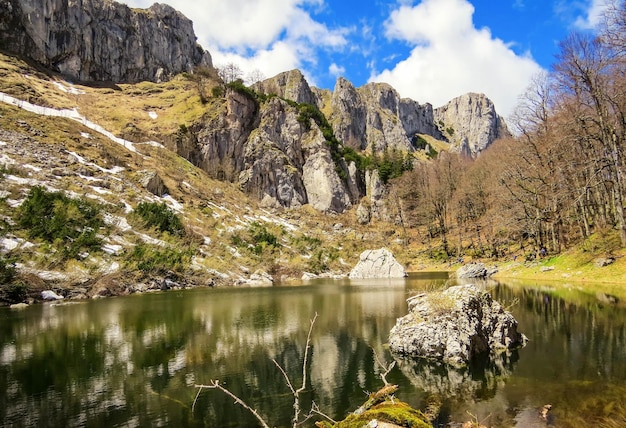 Piccolo stagno con rocce sullo sfondo sotto il cielo