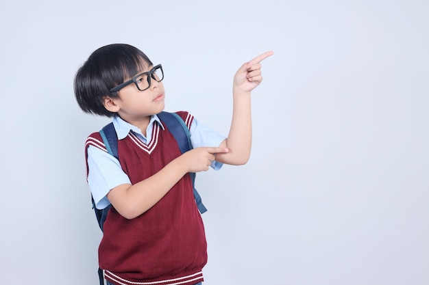Piccolo studente asiatico che indica da parte mostrando lo spazio di copia per la pubblicità