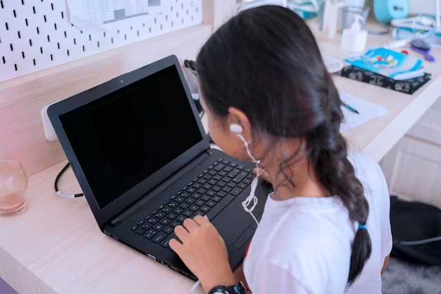 Piccolo studente che studia con il computer portatile a casa