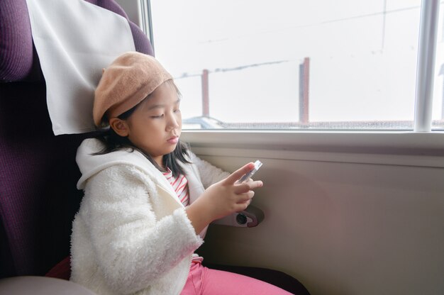 Piccolo viaggiatore gioca con il cellulare in treno