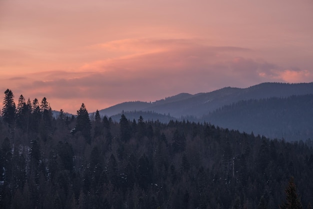 Piccolo villaggio alpino e montagne innevate invernali alla prima luce solare dell'alba intorno a Voronenko Carpazi Ucraina