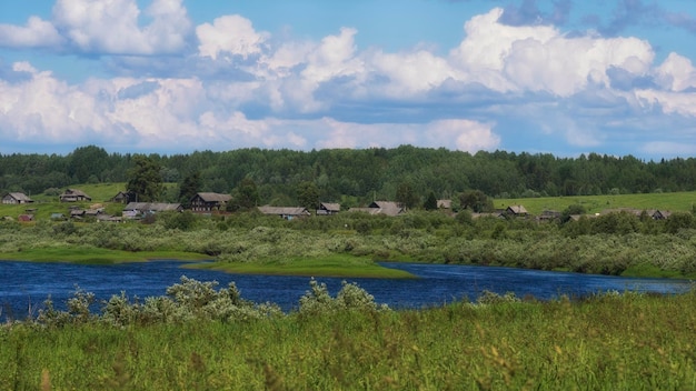 Piccolo villaggio con vecchie case di legno sulle rive del fiume in estate nella regione di Arkhangelsk