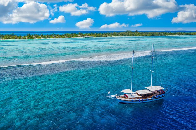 Piccolo yacht a vela nella barriera corallina tropicale del mare delle Maldive Costa dell'Oceano Indiano Paesaggio esotico dell'isola