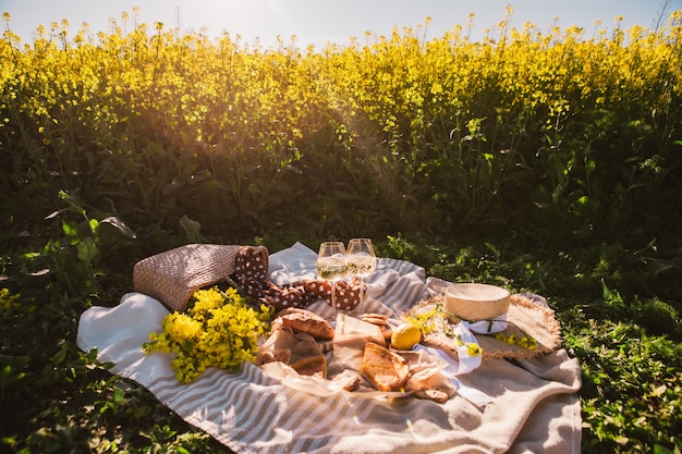 Picnic al tramonto al campo di colza bicchiere di vino cibo panino no people