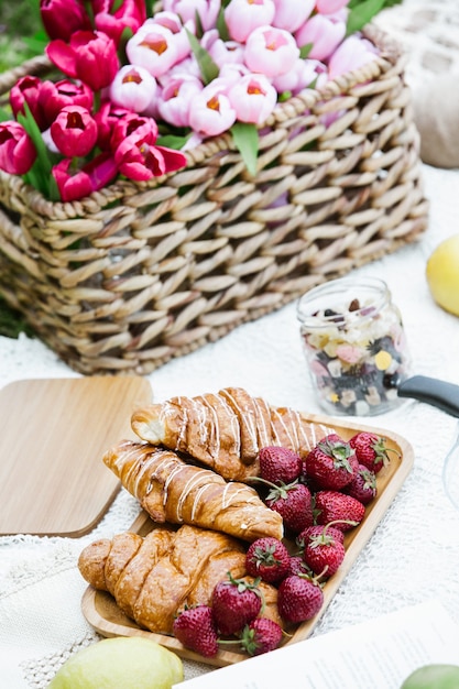 Picnic all'aperto in un lussureggiante parco verde con un gustoso croissant frutta ciambelle e vino sull'erba