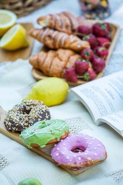 Picnic all'aperto in un lussureggiante parco verde con un gustoso croissant frutta ciambelle e vino sull'erba