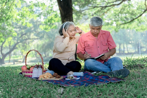 Picnic asiatico delle coppie anziane e relax sul prato verde in giardino