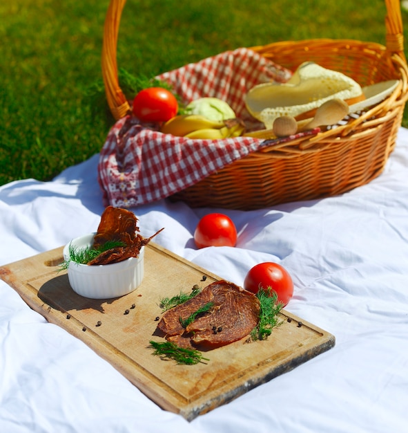 Picnic con carne di terrore su una tavola di legno e ingredienti freschi in un cestino