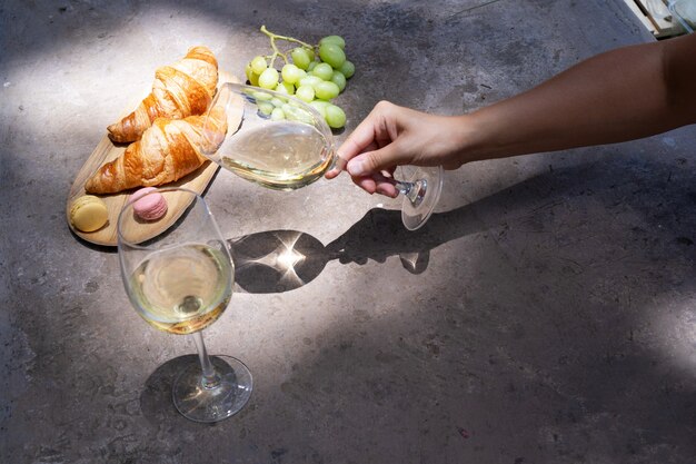 Picnic con vino bianco e croissant, qualcuno che tiene in mano un bicchiere, copia spazio sul tavolo