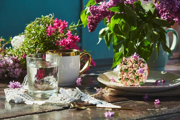 Picnic estetico in giardino con una tazza di caffè bellissimo cupcake bicchiere d'acqua fiori e decorazioni in pizzo Picnic del nucleo del cottage con luminosi toni estivi di fiori in una giornata di sole Ombre dure