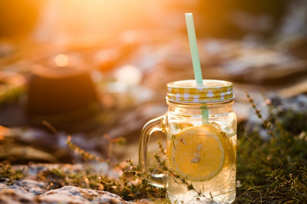 Picnic estivo all'aperto, barattolo di bevande estive con limonata, plaid alla calda luce del sole