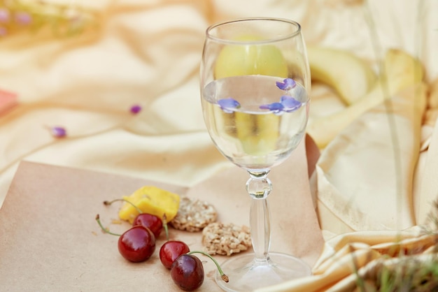 Picnic estivo bicchiere di vino viola lupini ciliegia halva biscotti su sfondo dorato artigianale Picnic estivo Posto per testo Vicinanza alla natura relax concetto di autoscoperta