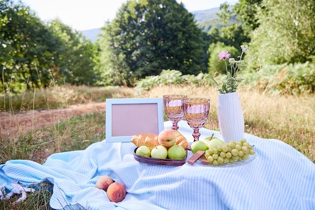 Picnic estivo con croissant, frutta, cioccolato e bicchiere di vino. Mock up frame place per il tuo testo