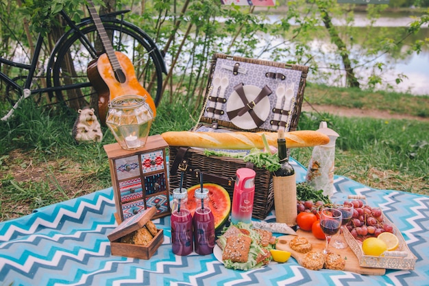 Picnic estivo di progettazione del primo piano in natura. Sul plaid c'è un cesto di cibo.