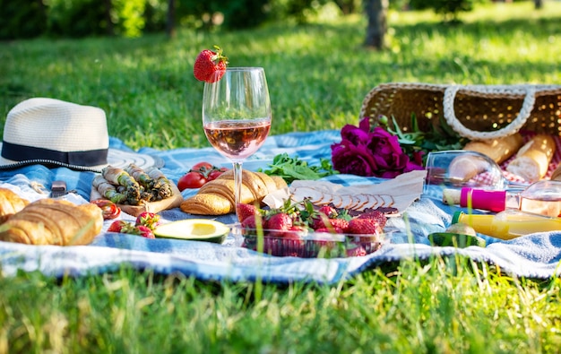 Picnic estivo nel parco sull'erba con vino, frutta e croissant