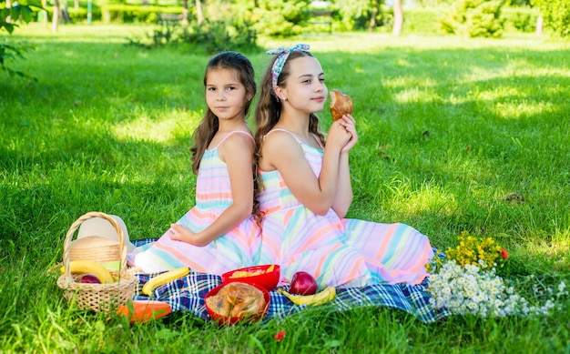 Picnic in famiglia. Le bambine mangiano un pasto da picnic sull'erba verde. Vacanze estive. Mangiare all'aperto. Goditi la giornata con cibo gustoso.