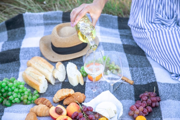 Picnic in natura, una ragazza e un uomo tengono in mano dei bicchieri con del vino. Messa a fuoco selettiva