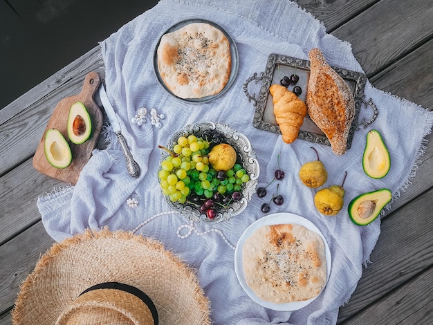 Picnic in stile vintage, frutta e pane con piatti vintage, decorazioni su fondo di legno vicino all'acqua, vista dall'alto