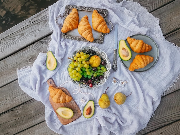 Picnic in stile vintage, frutta e pane con piatti vintage, decorazioni su fondo di legno vicino all'acqua, vista dall'alto