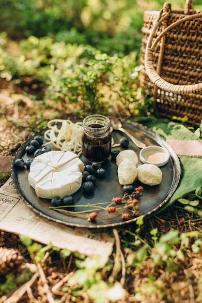 picnic nella foresta sullo sfondo di cespugli di muschio e mirtilli, formaggio e frutti di bosco su una lastra di metallo