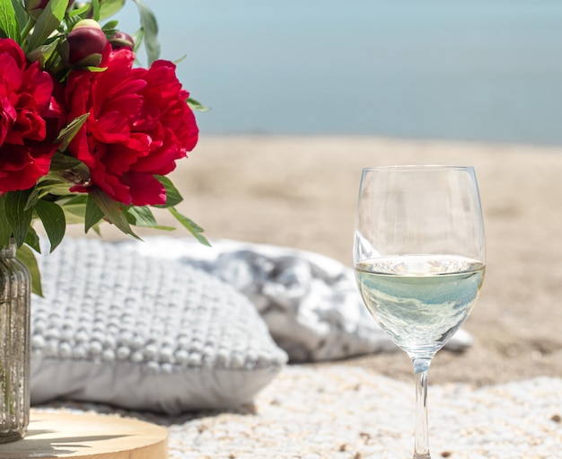 Picnic romantico con fiori e bicchieri di champagne in riva al mare. Il concetto di vacanza.