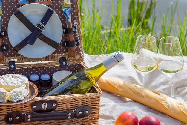 picnic sul lago: tovaglia, cestino da picnic con stoviglie, baguette