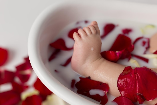 piede del bambino in un bagno di latte con petali rossi