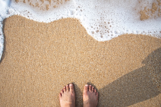 piede dell&#39;umano sulla sabbia e morbida onda sul mare.