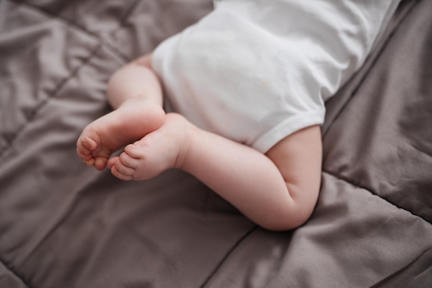 Piedi appena nati. Il bambino è sdraiato sul letto.