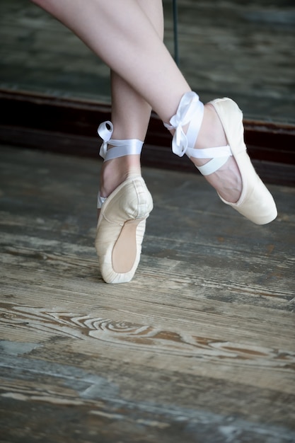 Piedi ballanti in ballerine sul pavimento di legno