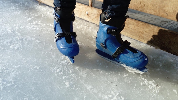 Piedi con pattini Divise e attrezzature sportive Pista di pattinaggio Ombre lunghe sul ghiaccio dal basso sole invernale