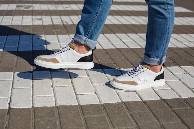 Piedi da uomo in sneakers bianche da tutti i giorni realizzate in pelle naturale su allacciatura.