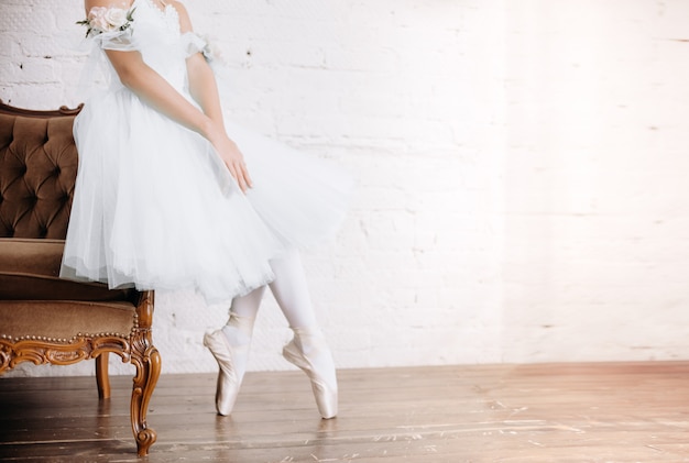 Piedi del ballerino di balletto sul pavimento dello studio. La ballerina adolescente mette le scarpe da punta