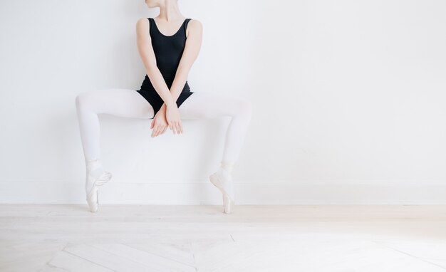 Piedi del ballerino di balletto sul pavimento dello studio. La ballerina adolescente mette le scarpe da punta