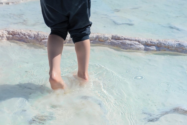 Piedi del bambino in piedi in acqua termale su terrazze calcaree bianche Concetto di salute e benessere Bellezza della natura