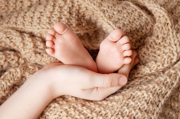 Piedi del bambino nelle mani del fratello. Primo piano dei piedi del neonato piccolo. Concetto di famiglia felice.