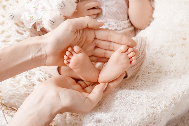 Piedi del bambino nelle mani della madre. I piedi minuscoli del neonato sul primo piano a forma di femminile delle mani