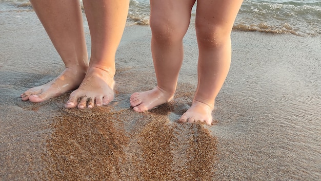 Piedi del bambino nelle onde del mare