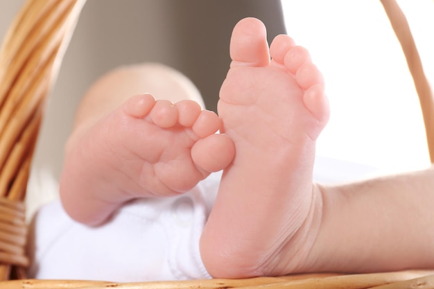 Piedi del piccolo bambino sveglio che si trova nel primo piano del canestro di vimini