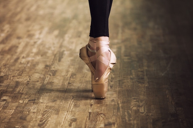 Piedi della ballerina in scarpe da ginnastica sul pavimento in legno parquet si chiudono in stile retrò