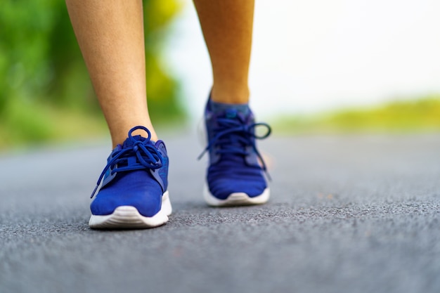 Piedi della donna che corrono sulla strada