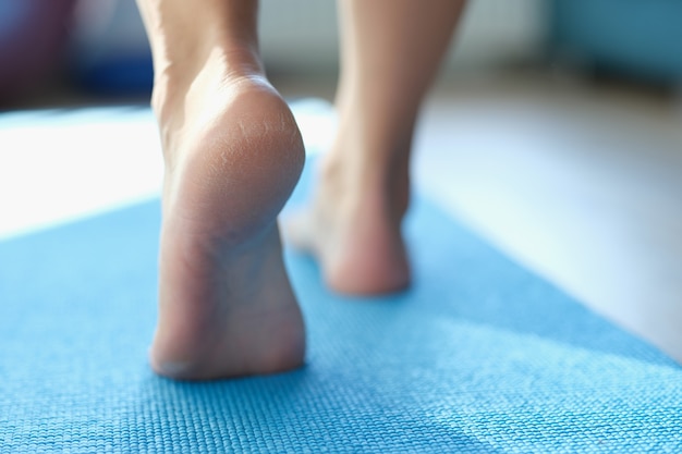 Piedi delle donne che camminano sulla stuoia di sport con pelle asciutta sul primo piano dei talloni