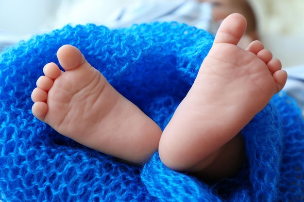 Piedi di bambino carino coperto con coperta blu vista ravvicinata